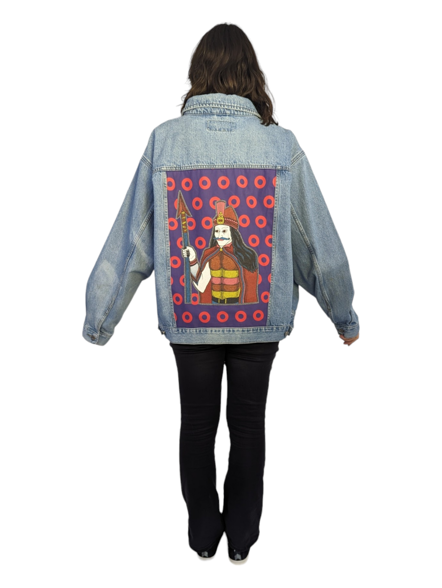 Rear view of woman wearing upcycled men's denim jacket with Phish patches on back.